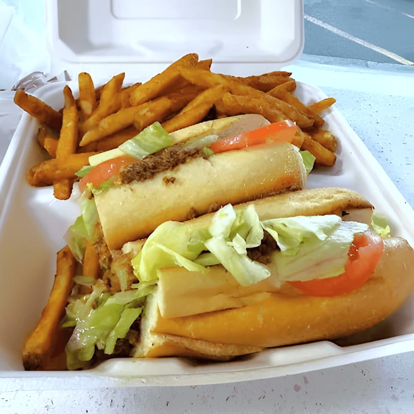 Two Chopped Cheese House sandwiches with lettuce and tomato, alongside a pile of golden french fries.