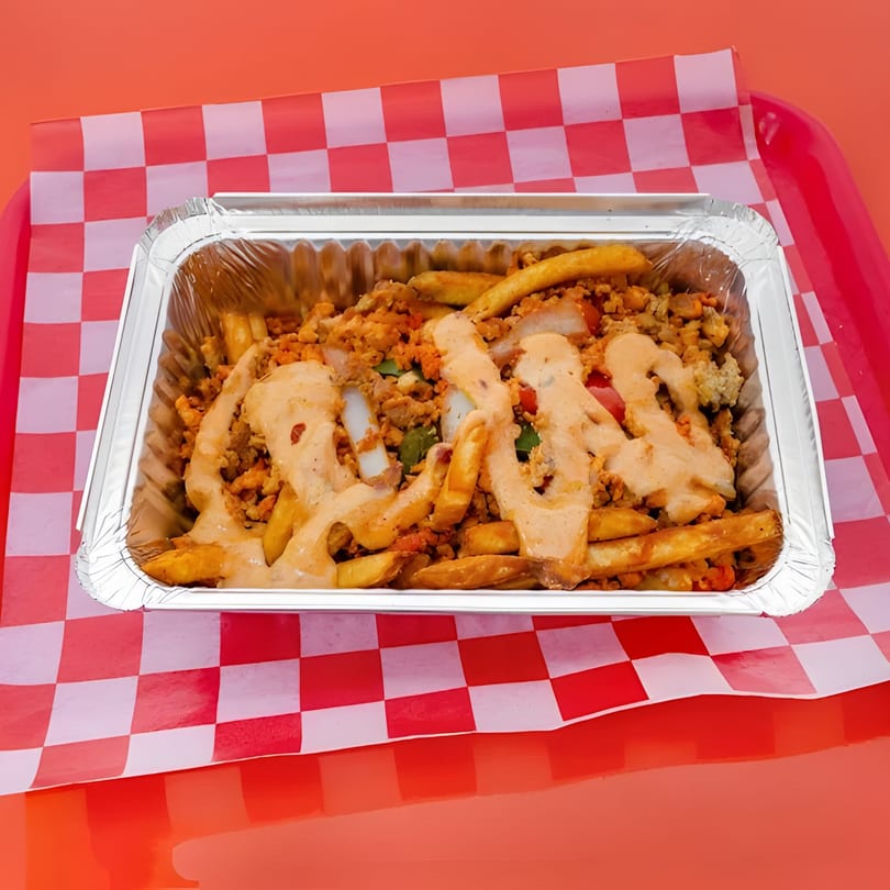 Chopped Cheese House's chopped cheese fries, topped with sauce, in a foil container on a red and white checkered paper.